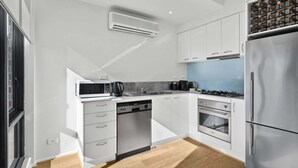 Une cuisine moderne avec des meubles blancs, un réfrigérateur en acier inoxydable, un four à micro-ondes, une machine à café et un lave-vaisselle.