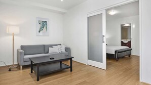 Un salon moderne avec un canapé gris, une table basse noire et un lampadaire.
