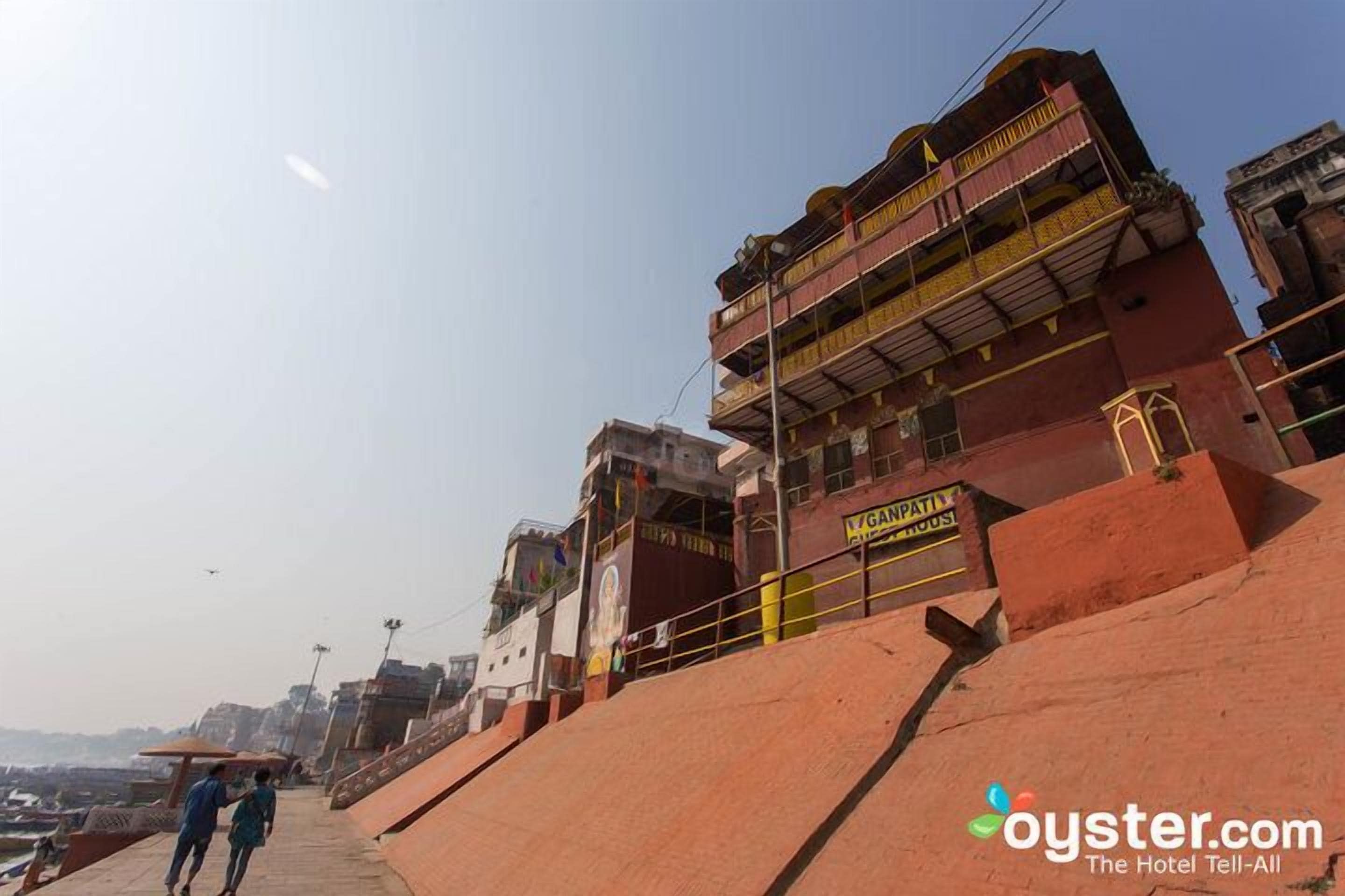 A hotel with a red facade, a signboard, and a staircase leading to the entrance.