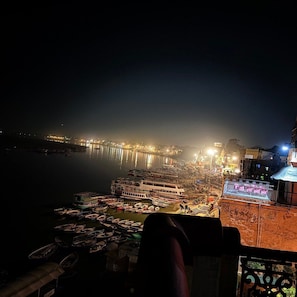 A nighttime view of a riverside area with boats docked along the shore and buildings illuminated in the background.