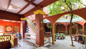 A spacious indoor area with a staircase, multiple seating areas, and a central tree.