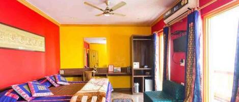A room with two beds, a ceiling fan, a wardrobe, and a window with curtains.