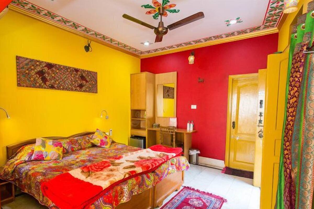 Una habitación con cama, ventilador de techo, espejo y puerta.
