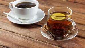A cup of tea with a lemon slice on a saucer and a cup of black coffee on a wooden table. - Sudana Homestay Ubud (Ubud)