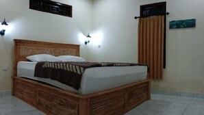 A bedroom with a wooden bed, two wall-mounted lights, a window with curtains, and a ceiling with recessed lighting. - Sudana Homestay Ubud (Ubud)