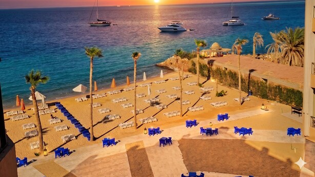 Ein Hotel direkt am Strand mit Meerblick, Liegebereichen und Booten.