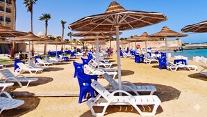 Ein Strandresort mit Liegestühlen, Sonnenschirmen und freiem Blick auf das Meer.