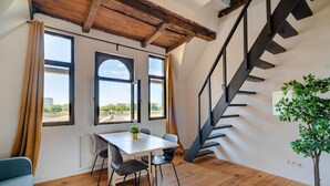 A room with a wooden floor, a dining table with chairs, a staircase, and a potted plant. - Two-bedroom Apartment by the River (Antwerp)
