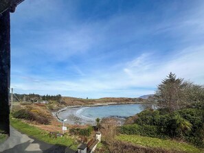 A coastal landscape with a curved beach, greenery, and a clear sky. - Avocet Apartment - UK51130 (Carradale)
