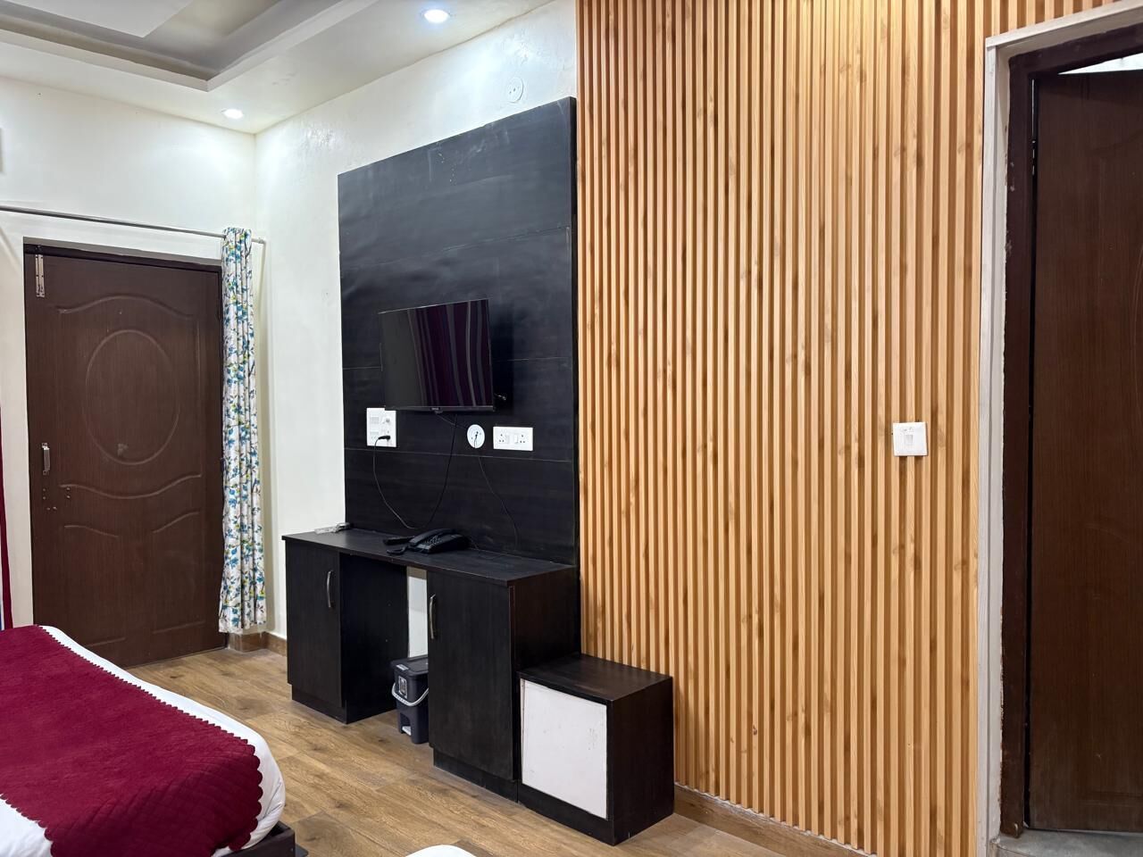 Un dormitorio con cama, televisión, escritorio y pared de paneles de madera.