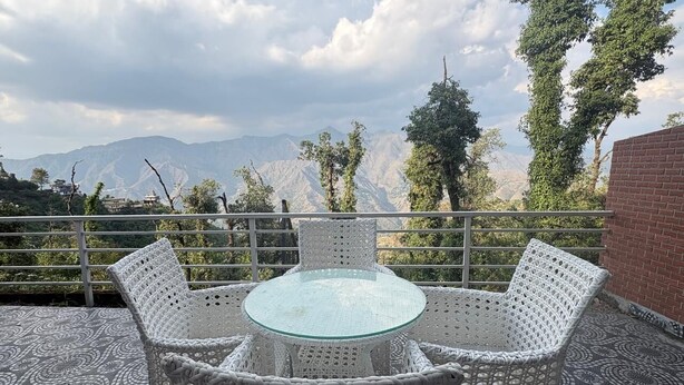 A round glass table with white wicker chairs on a patterned floor, overlooking mountains. - Grand vista retreit  (Mussoorie)