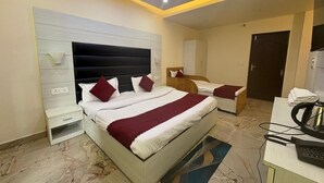 A hotel room with a bed, bedside tables, a desk with a telephone, and a ceiling fan. - Grand vista retreit  (Mussoorie)