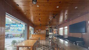 A restaurant with wooden interiors, a long dining table, and a counter. - Grand vista retreit  (Mussoorie)