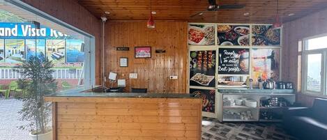 A wooden reception desk, a reception area, and a wall with food images and a sign saying 'People to eat are always the best people.'