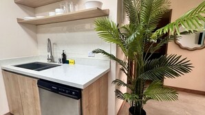 A kitchen with a dishwasher, a sink, and a potted plant. - Comfortable 2BR Condo in Coco at Nangu (Coco)