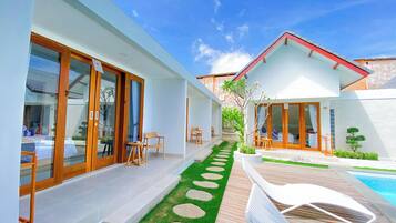 A modern house with a pool, a patio with lounge chairs, and a garden with stepping stones.