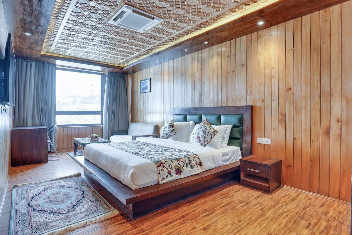 A wooden-paneled bedroom with a large bed, a nightstand, and a window with curtains.