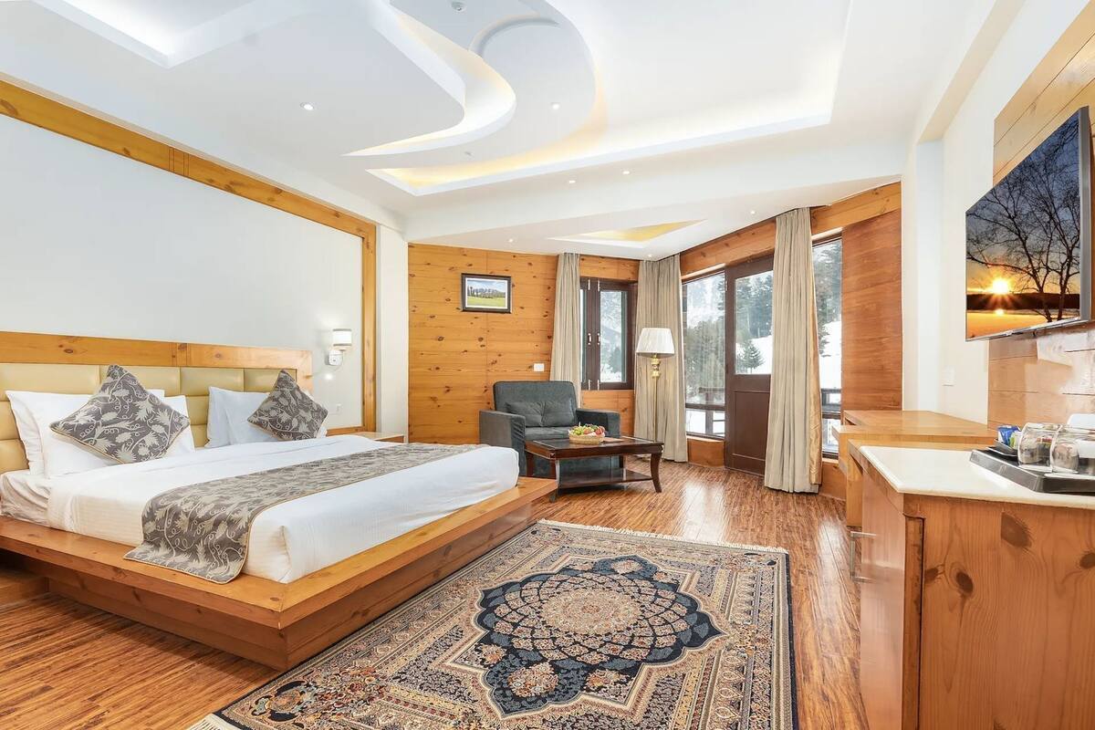 A hotel room with a large bed, a desk, a chair, and a view of the outdoors.
