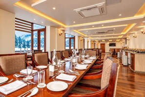 Un comedor con mesas largas dispuestas para varios comensales, equipado con sillas, vajilla y cristalería.