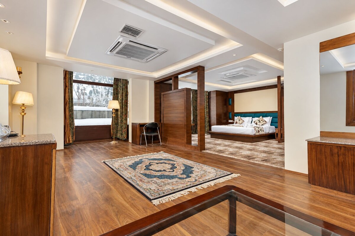 Habitación de hotel con una cama grande, un escritorio, una silla y vistas al exterior.
