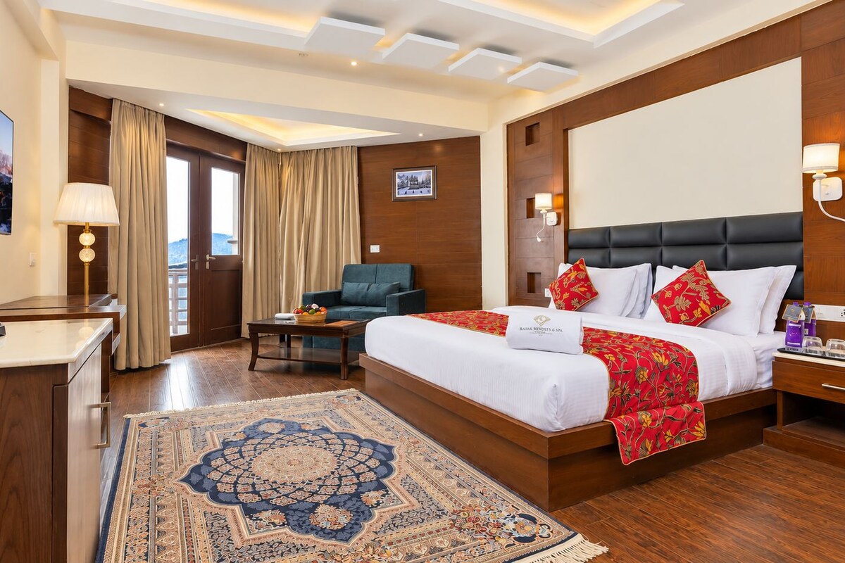 Habitación de hotel con una cama grande, un escritorio, una silla, un televisor y vistas al exterior.