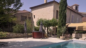 A pool area with a stone building, outdoor furniture, and a clear sky. - La Maison Soleil du Levant (Sérignac)