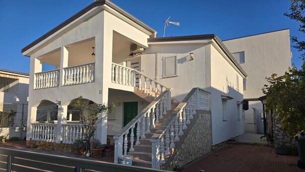 A two-story building with a balcony, a staircase, and a small garden area. - Serene Holiday Home in Vir near Sea (VIR)
