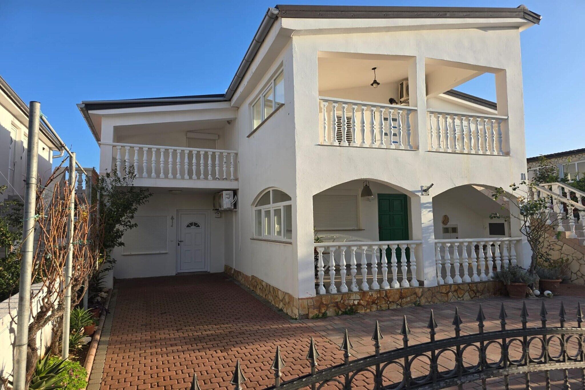 Ein zweistöckiges Gebäude mit Balkon, Garage und Steinunterbau.