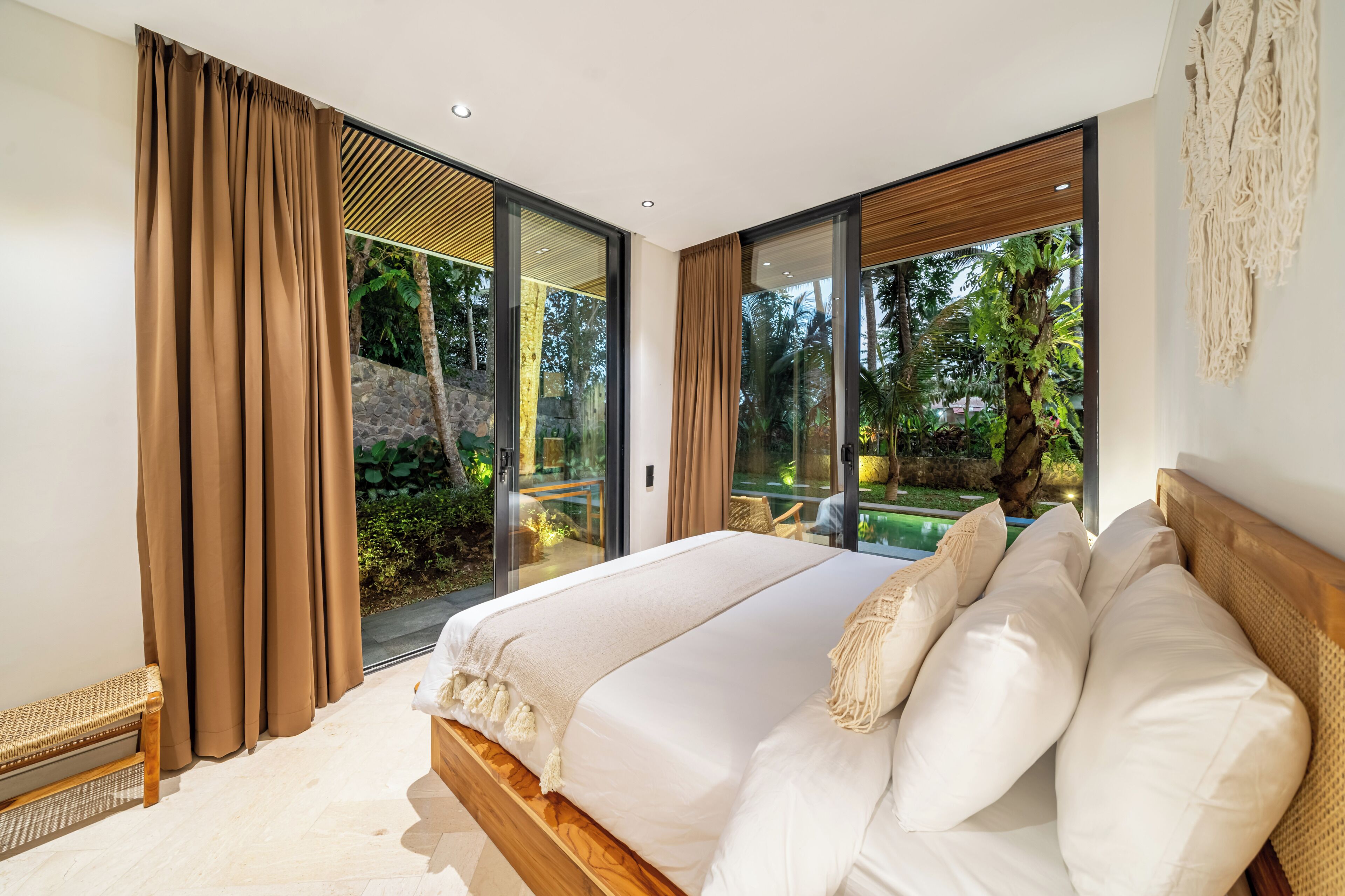 Un dormitorio con una cama grande, puertas de vidrio correderas que dan a un balcón y vistas a zonas verdes.