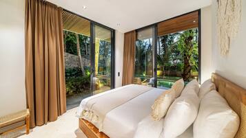 Un dormitorio con una cama grande, puertas de vidrio correderas que dan a un balcón y vistas a zonas verdes.