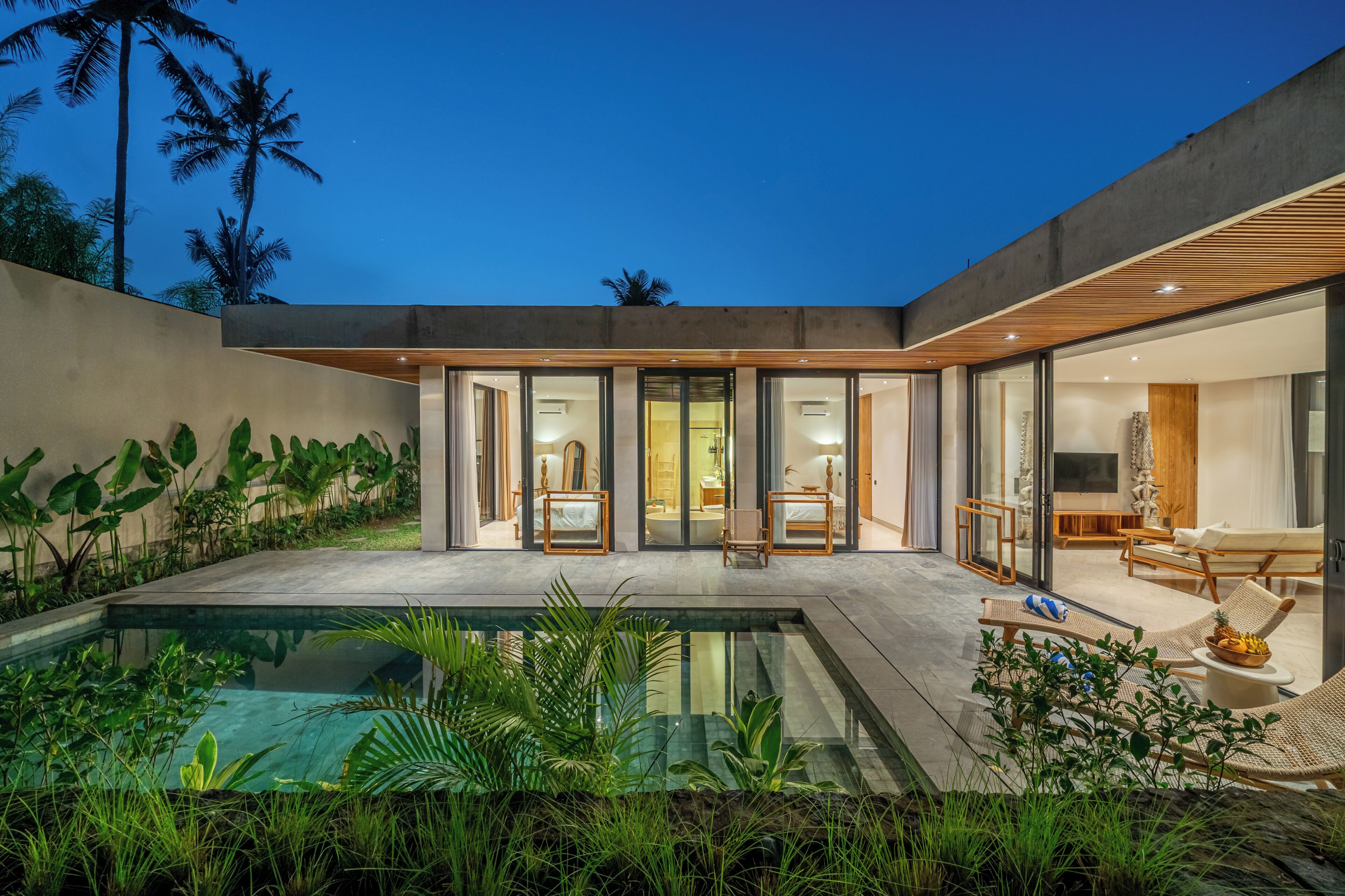 Una casa moderna con piscina, puertas de vidrio y un área de descanso.