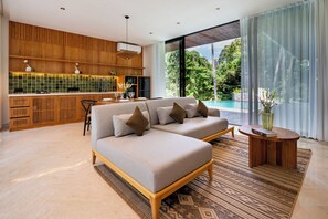 A modern living room with a sofa, a dining area, and a view of a swimming pool. - Happiness Residence Ubud (Ubud)