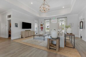 A spacious living area with a flat-screen TV, a coffee table, a sofa, and a large vase. - The Saraland (Mobile)