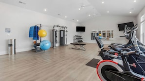 Ein Fitnessraum mit Trainingsgeräten, einem Fernseher und einem Fenster.