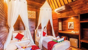 Una habitación con dos camas, cada una con dosel, paredes de madera y un equipo de aire acondicionado.