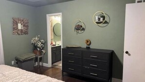 Een slaapkamer met een bed, een dressoir en een spiegel.