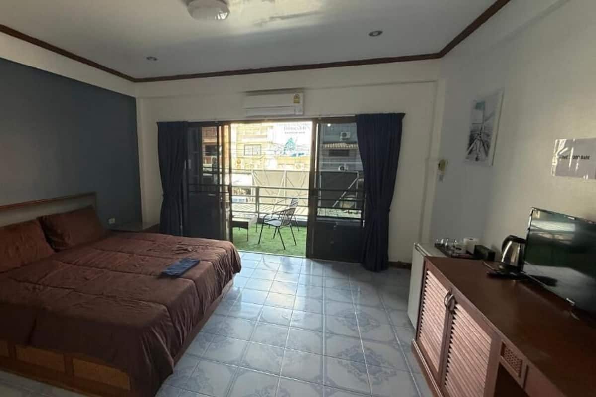 Un dormitorio con cama, escritorio, televisor y vistas al exterior.