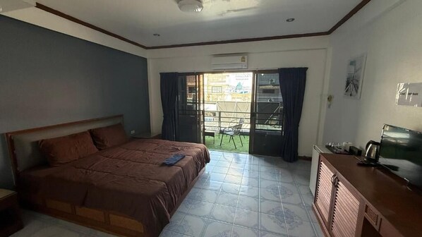 Un dormitorio con cama, escritorio, televisor y vistas al exterior.