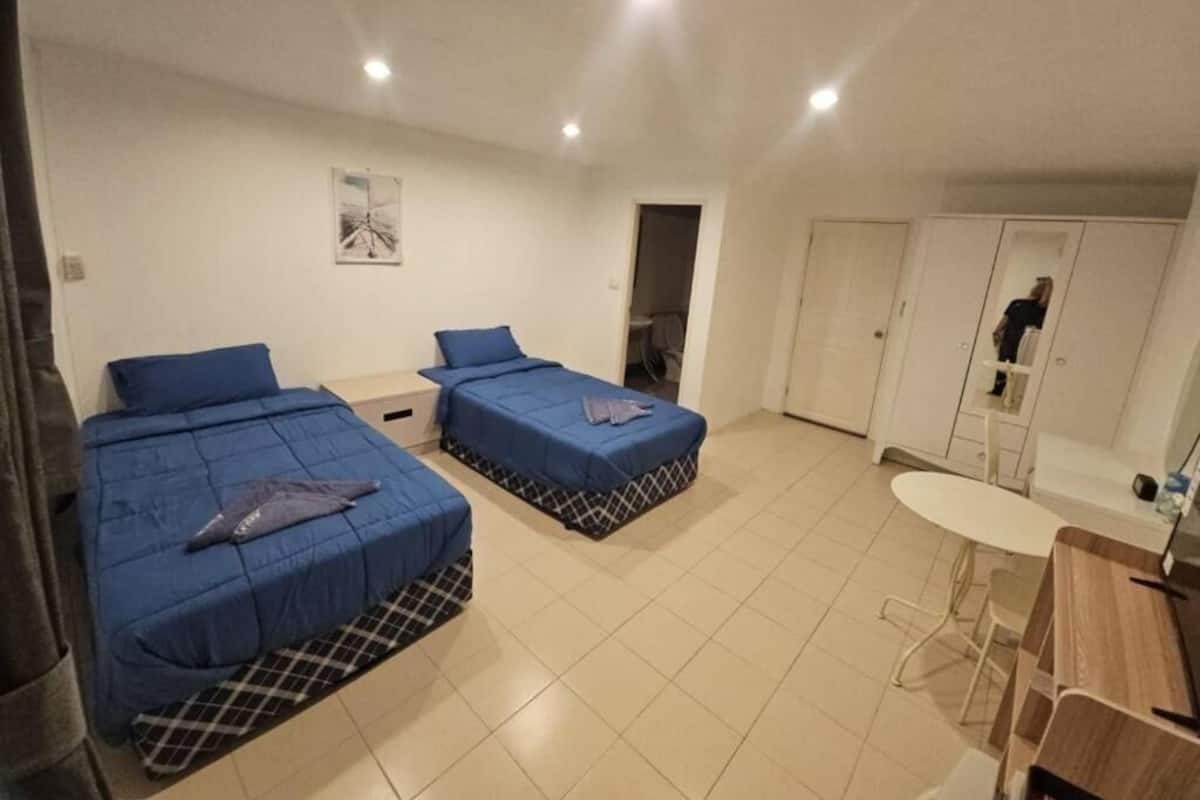 Una habitación con dos camas, una mesita y un armario.