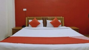 A bed with a wooden headboard, two pillows, and a red blanket. - Hotel GSA and BANQUET (Haridwar)