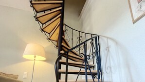 En spiraltrappa med ett metallräcke, en lampa och en inramad tavla på väggen.