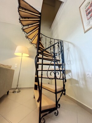 Eine Wendeltreppe mit Metallgeländer, einer Lampe und einem gerahmten Bild an der Wand.