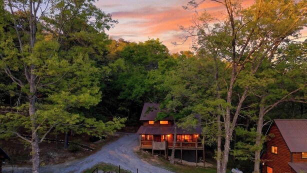 A cabin with a fire pit and outdoor seating, surrounded by dense forest. - 6BR Cabin Trio + Hot Tubs | Quiet Side of Smokies | Isaiah's, Jack's & Elijah's (Townsend)