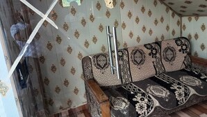A room with patterned wallpaper, a sofa with a floral design, and a metal pole.
