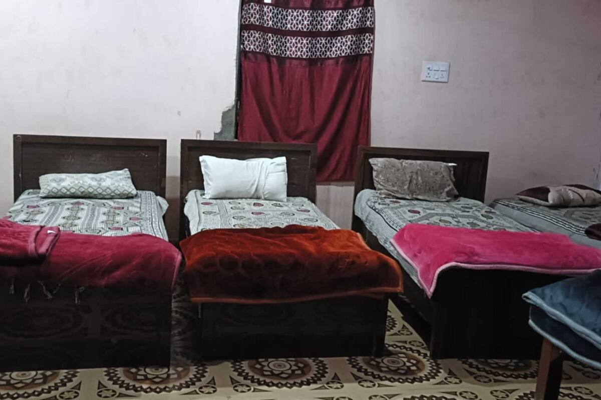A room with three beds, a heater, and a patterned rug.