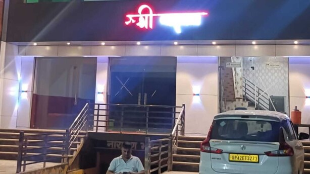 A hotel with a prominent 'HOTEL' sign, a staircase leading to the entrance, and a parked car in front.