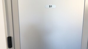 Puerta metálica de ascensor con un letrero que dice 'S1' y un teclado numérico a la izquierda.