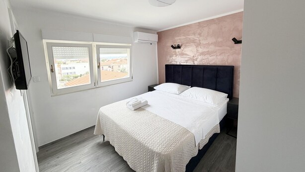 Un dormitorio con cama, ventana, aire acondicionado y luz en el techo.