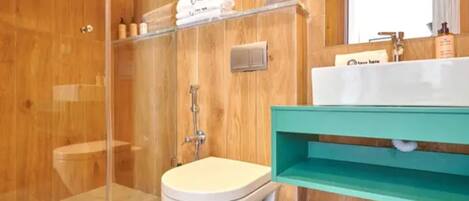 A wooden bathroom with a toilet, shower, and a sink with a mirror.
