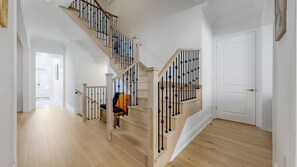 Eine Treppe mit Holzbodenstufen und schwarzen Geländern, die zu einer weißen Tür führt.